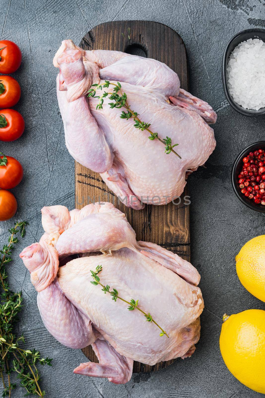 Whole raw free range fresh chicken with herbs and ingredients, on gray background, top view