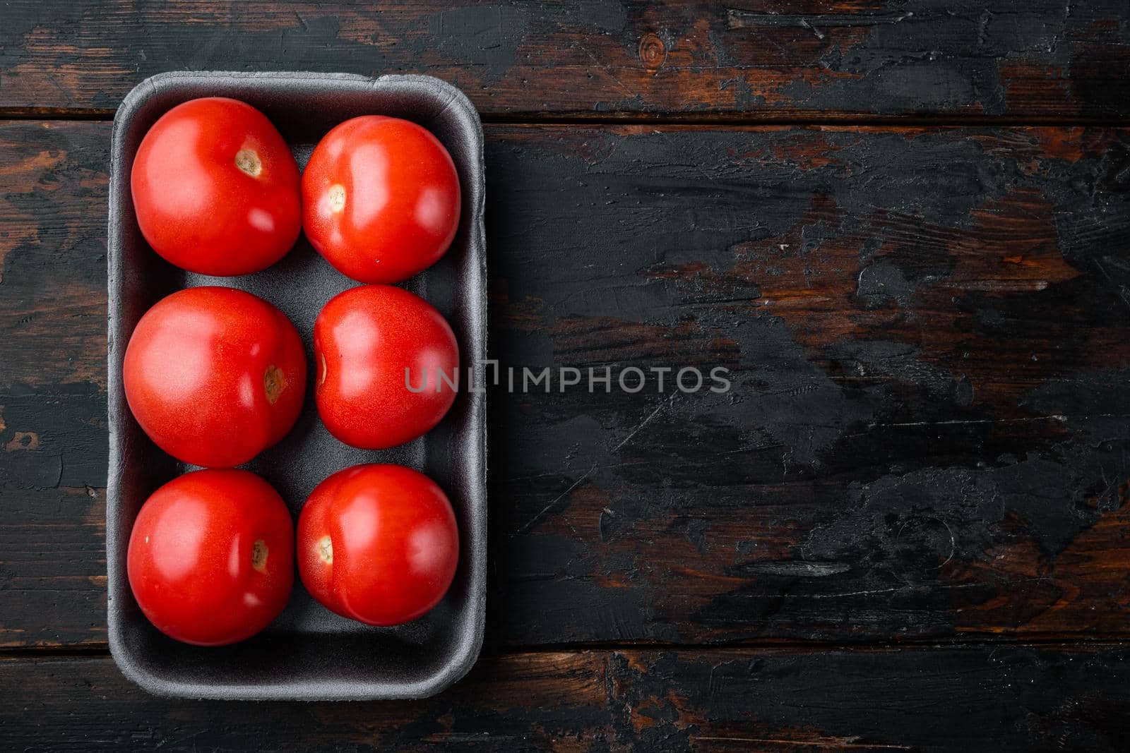 Red ripe tomatoes, on dark wooden background with copy space for text