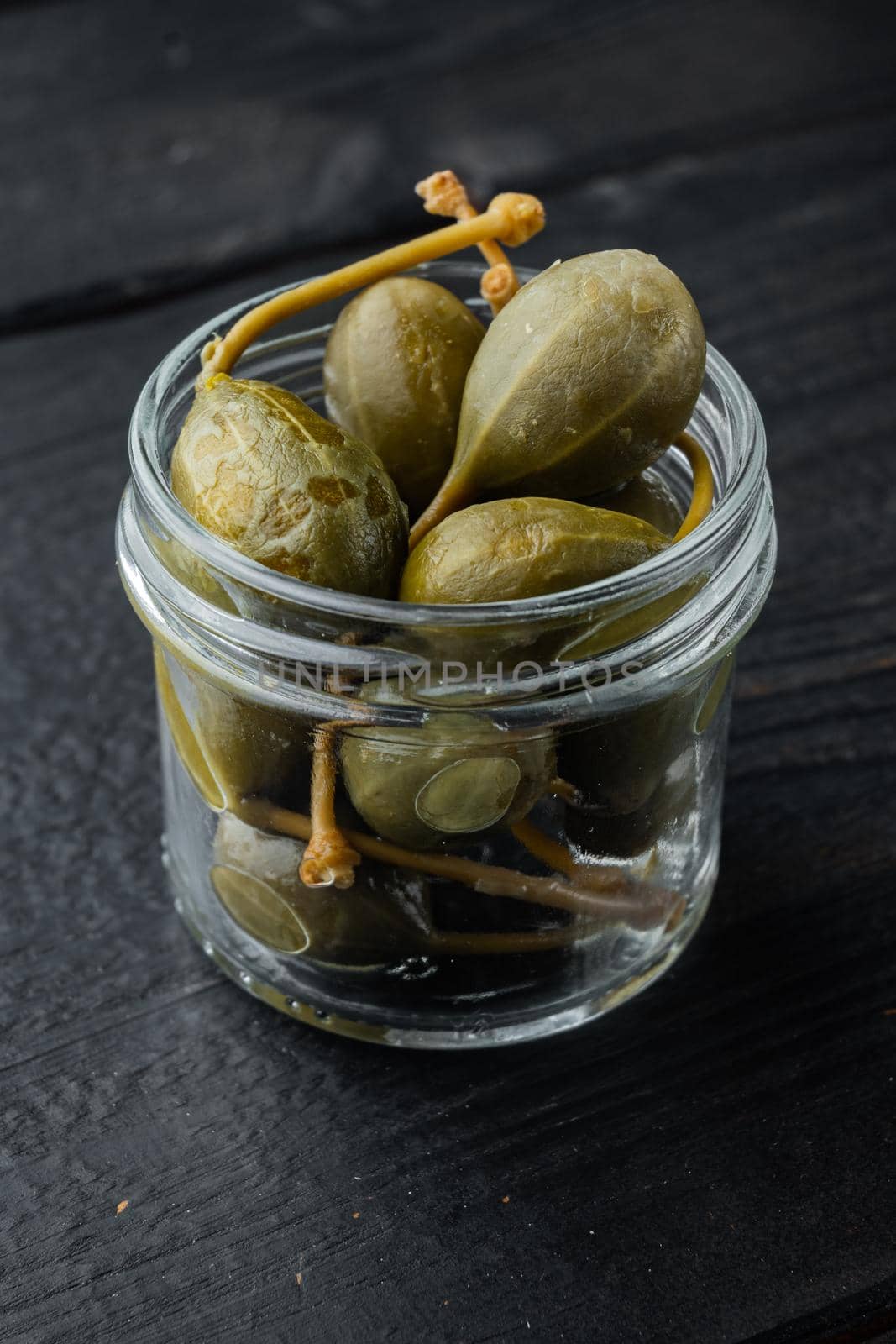 Organic pickled, canned capers, on black wooden background
