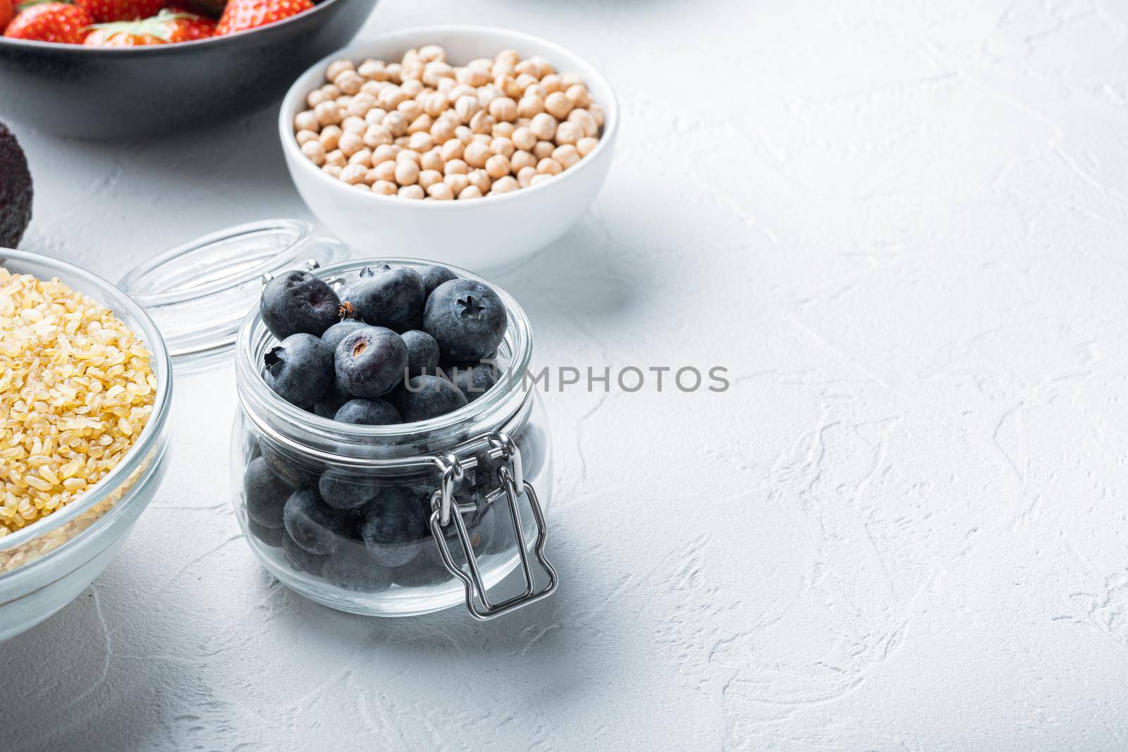 Ripe blueberry in glass jar with space for text, on white background.