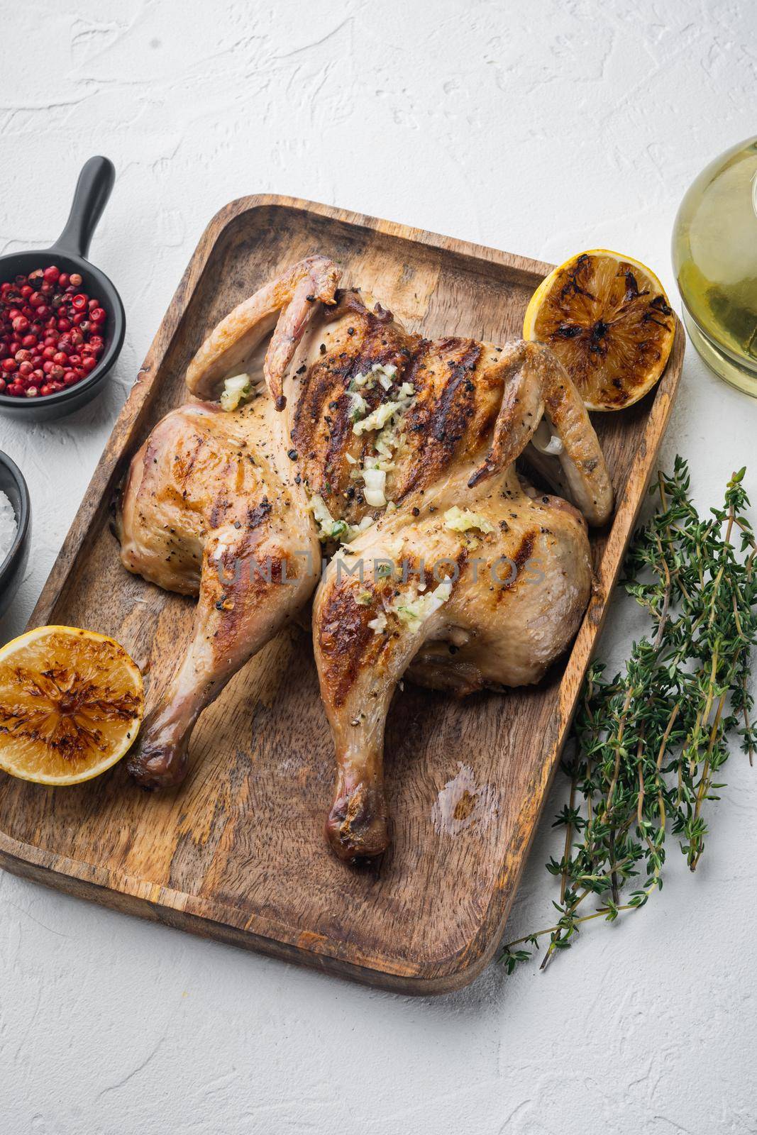 Butterflied rotisserie chicken with crispy golden skin, on white background