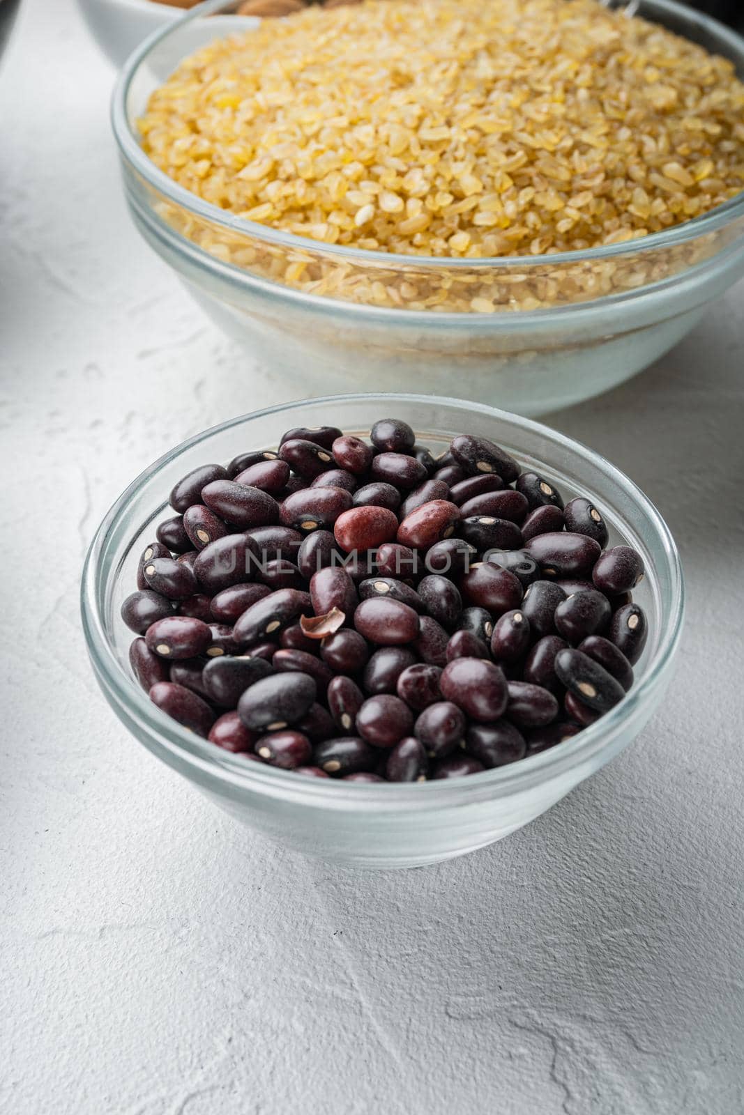 Red beans in bowl with healthy ingredients, on white background.