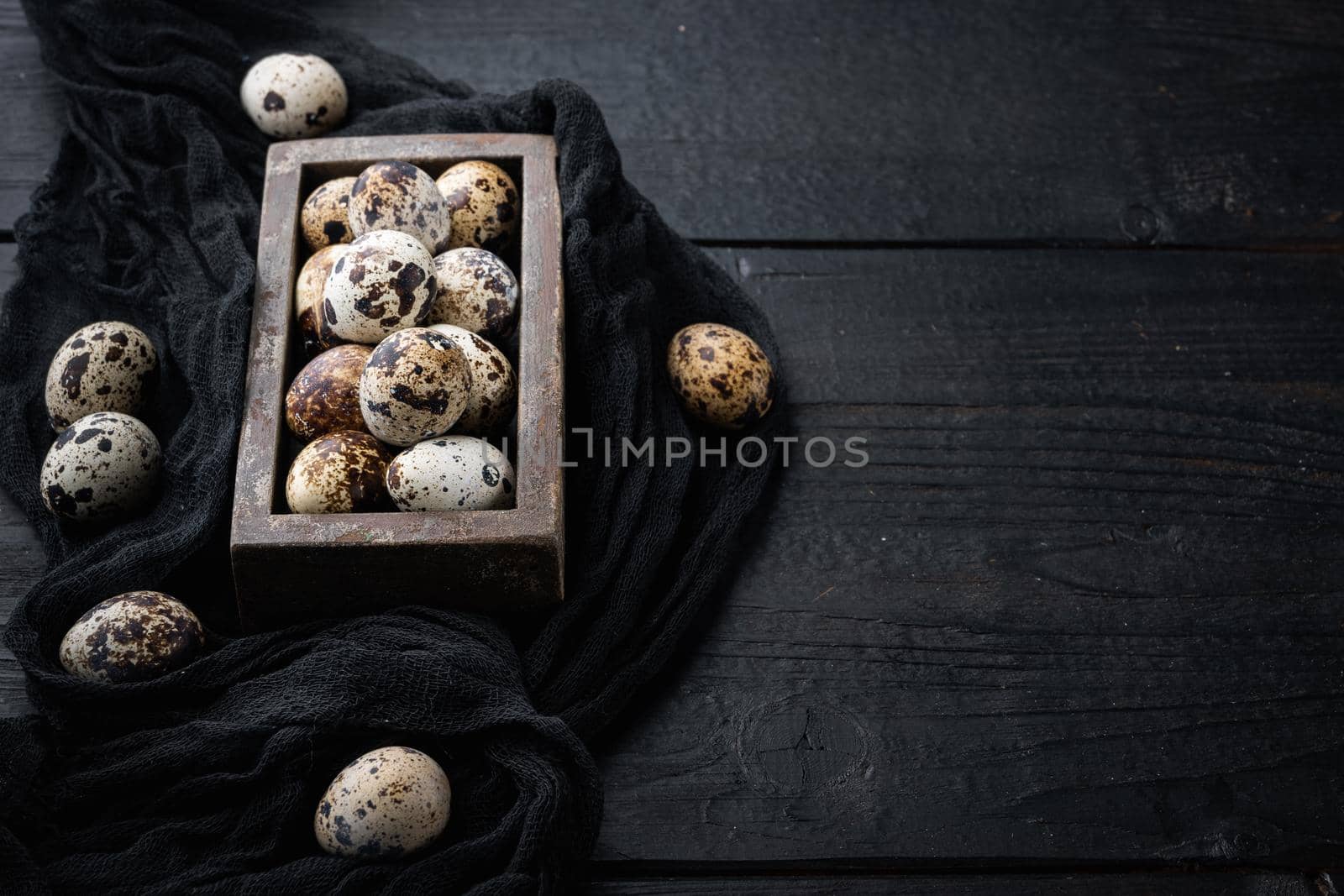 Organic quails eggs, on black wooden background with space for text