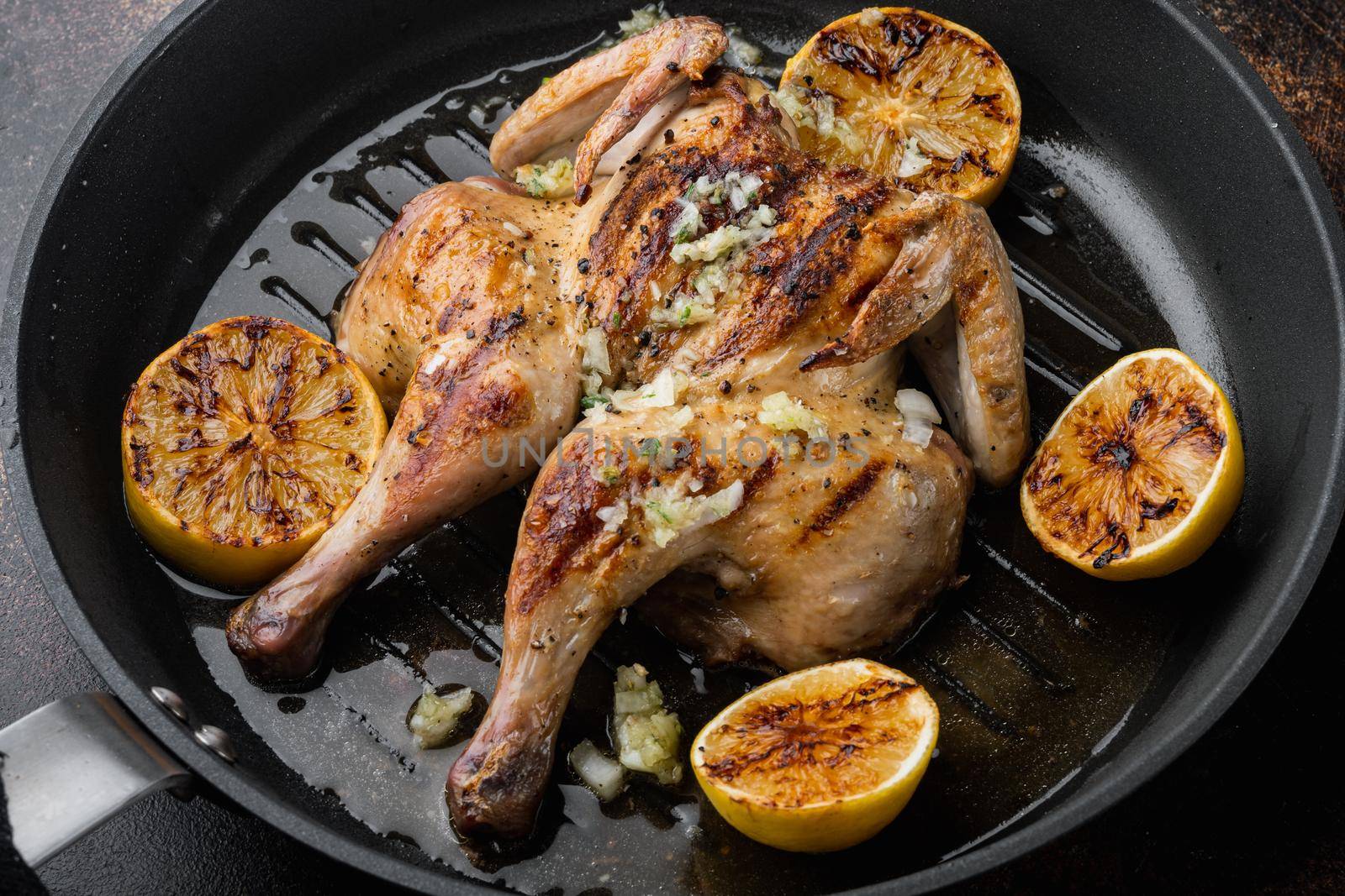 Grilled fried roast chicken tabaka with herbs, on old rustic background