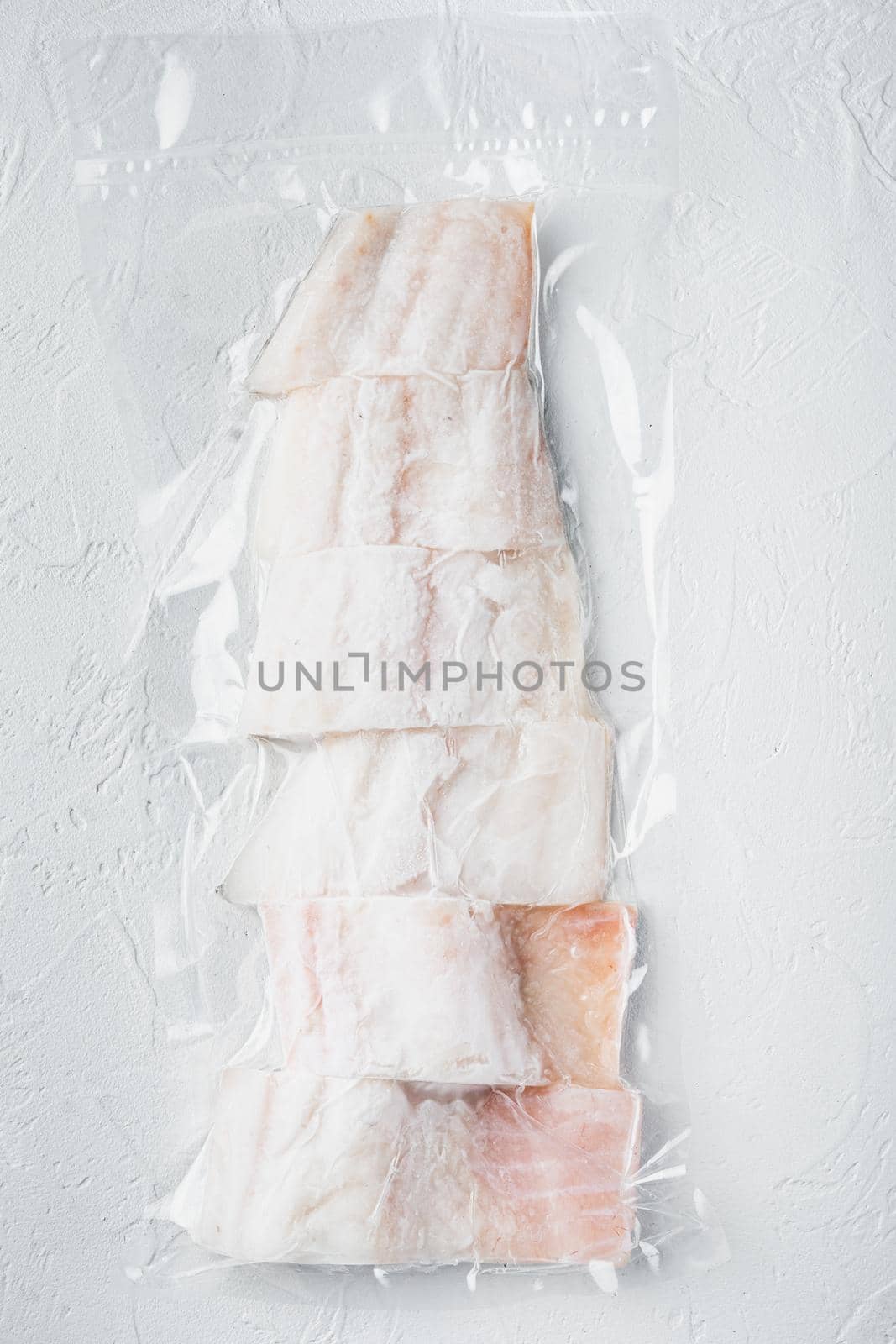 Raw haddock fish skinless plastic vacuum packaged, on white background, top view