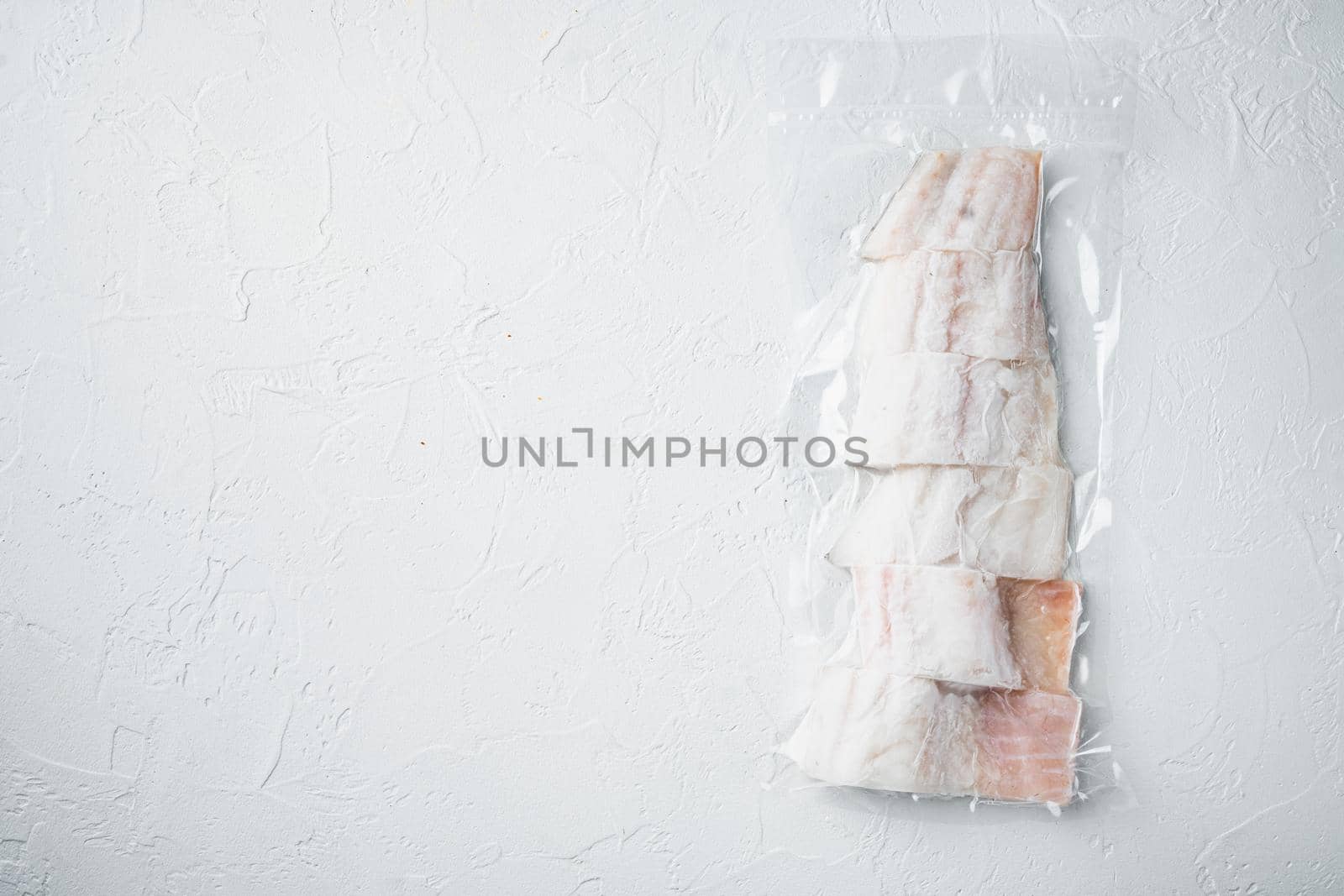 Haddock white fish fillet in plastic market package, on white background, top view with copy space for text