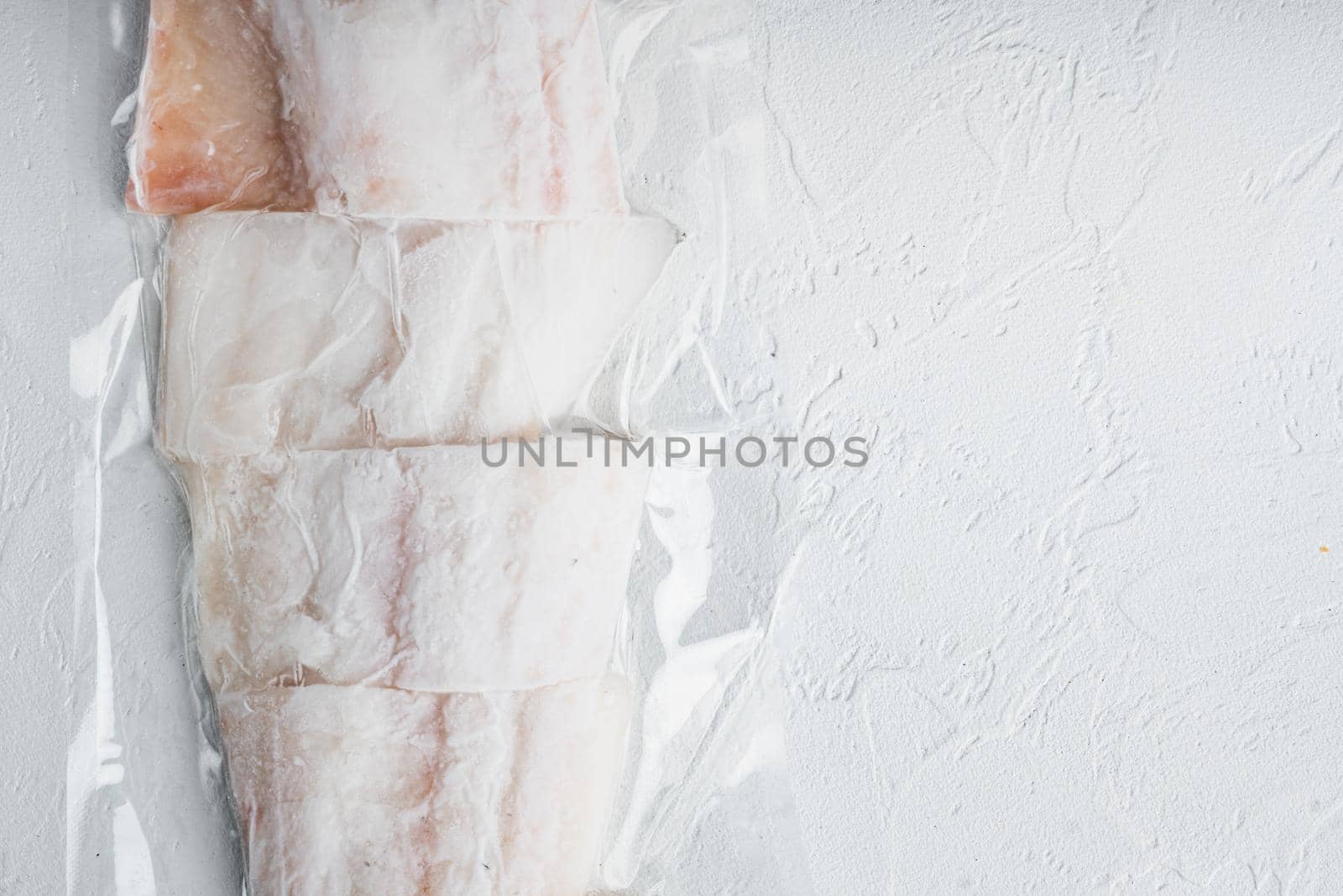 Haddock white fish fillet in plastic market package, on white background, top view with copy space for text