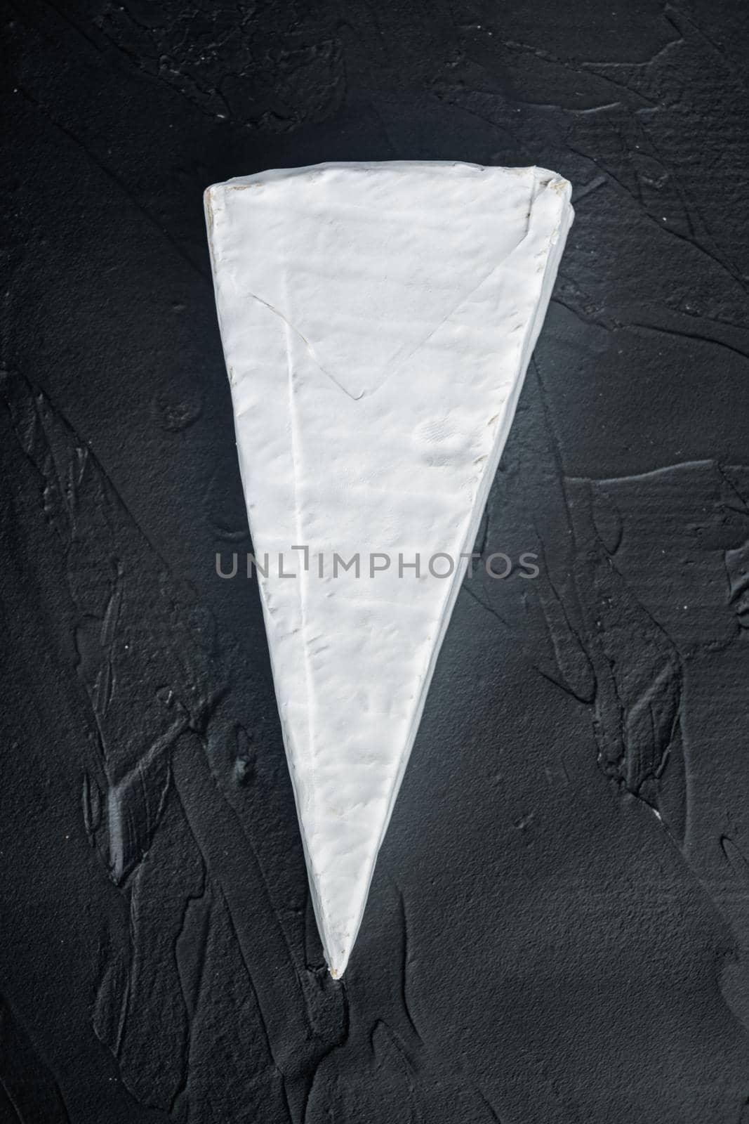 Piece of the brie cheese set, on black background, top view