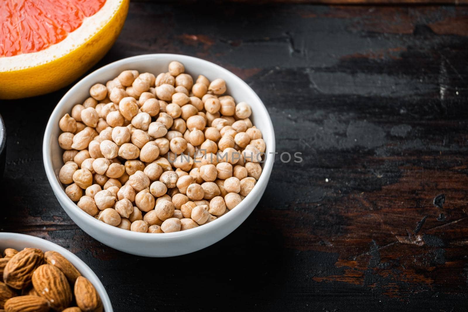 Chickpea in white bowl on dark wooden background, with copy space.