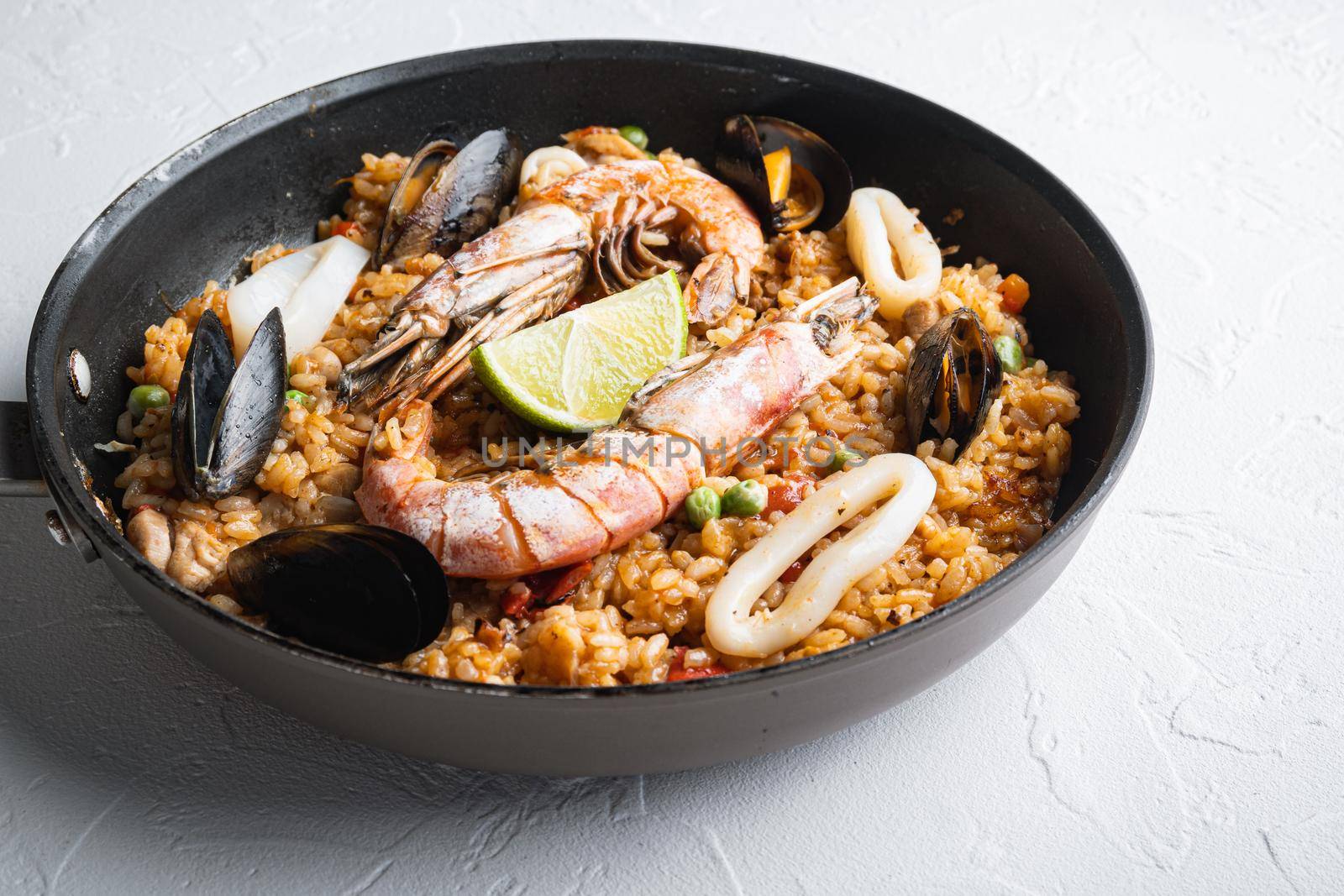 Paella with seafood and chicken on white background, food photo.