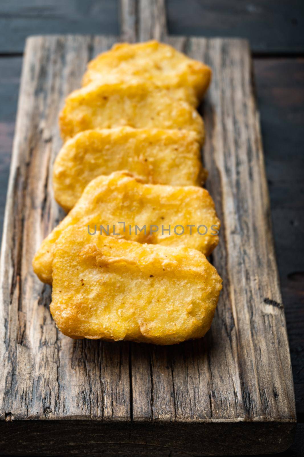 Homemade chicken nuggets fried on dark wooden background.