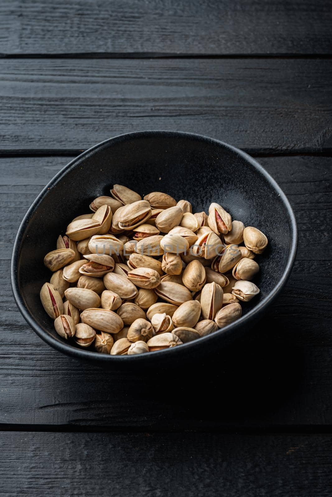 Shelled, unsalted pistachios, on black wooden table