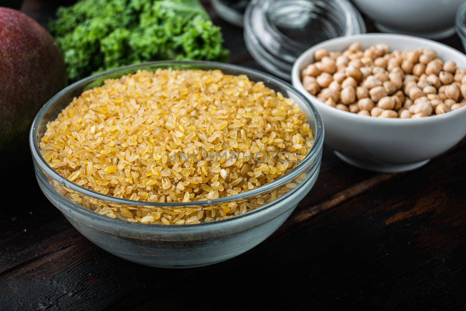 Bulgur grain in bowl on dark wooden background.