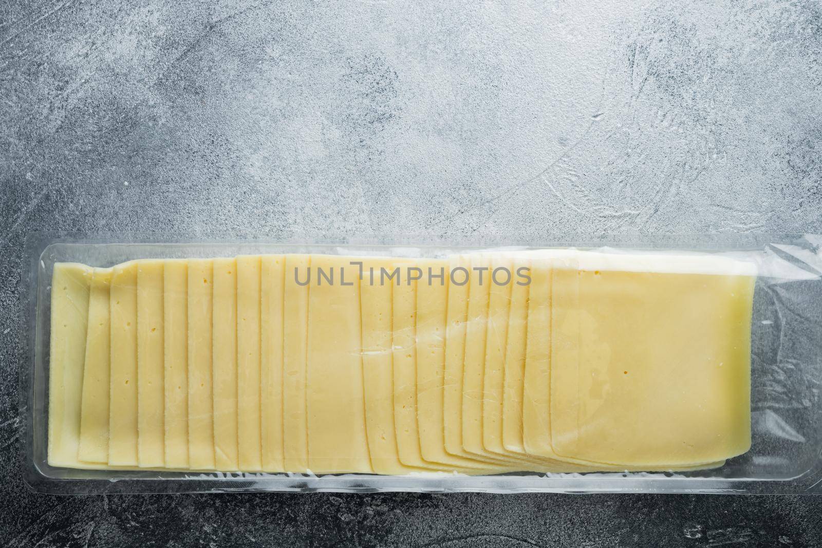 Cheddar cheese in vacuum pack, on gray background with copy space for text