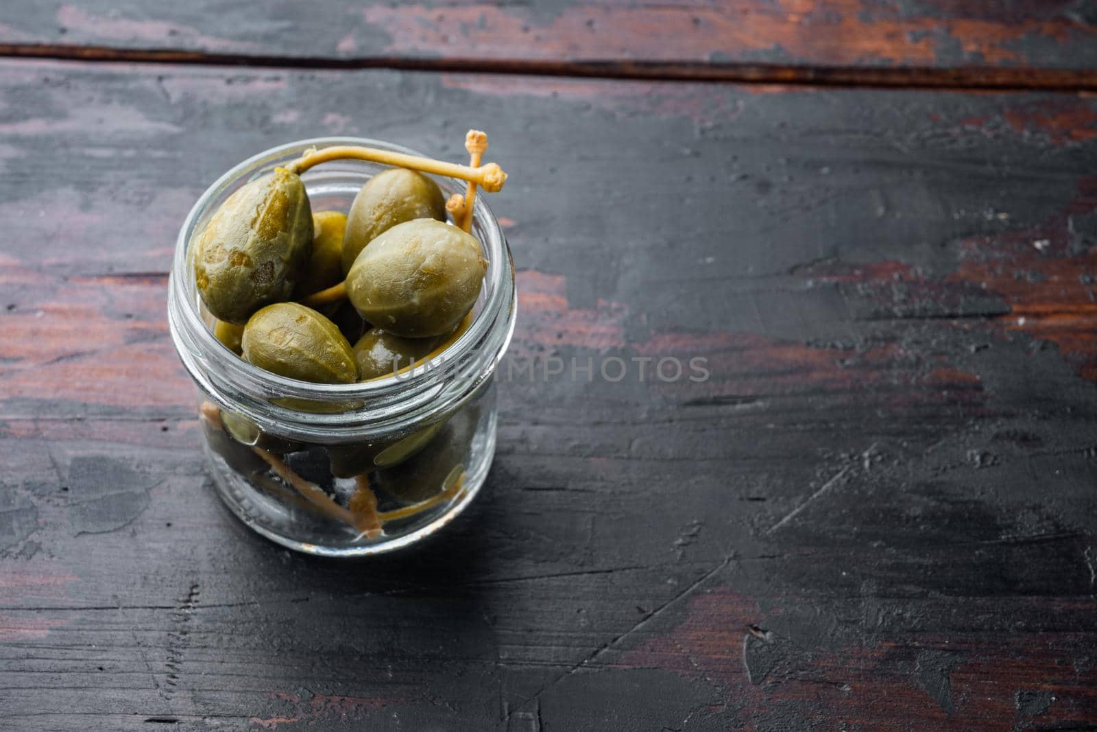 Organic pickled, canned capers, on old wooden table with copy space for text