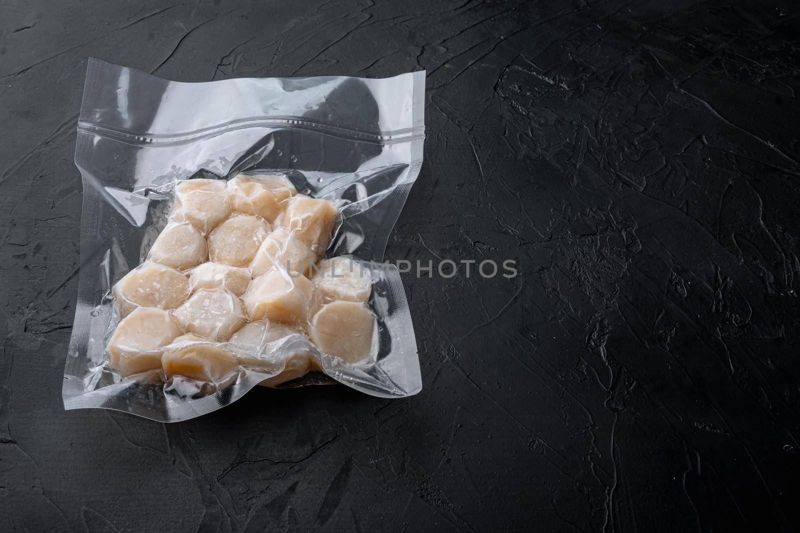 Scallops, in vacuum pack, on black textured background with copy space