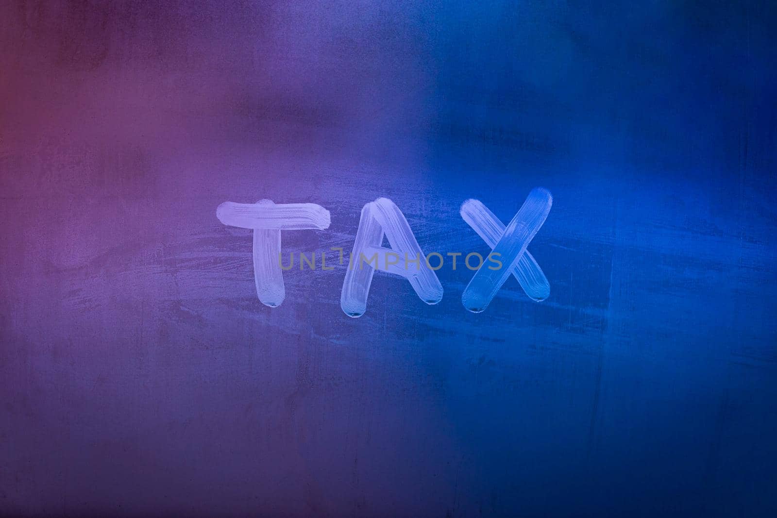 word tax hadwritten on night wet window glass surface with blue and purple colors in blurry background