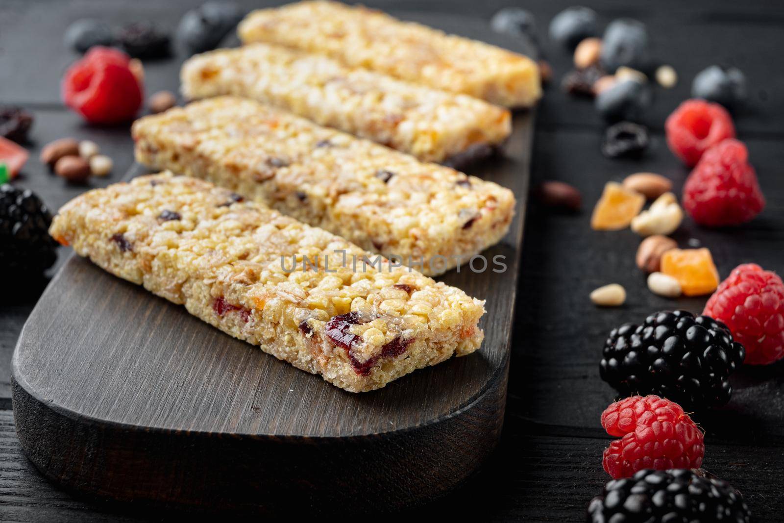 Granola bar with raisins and berry, on black wooden table