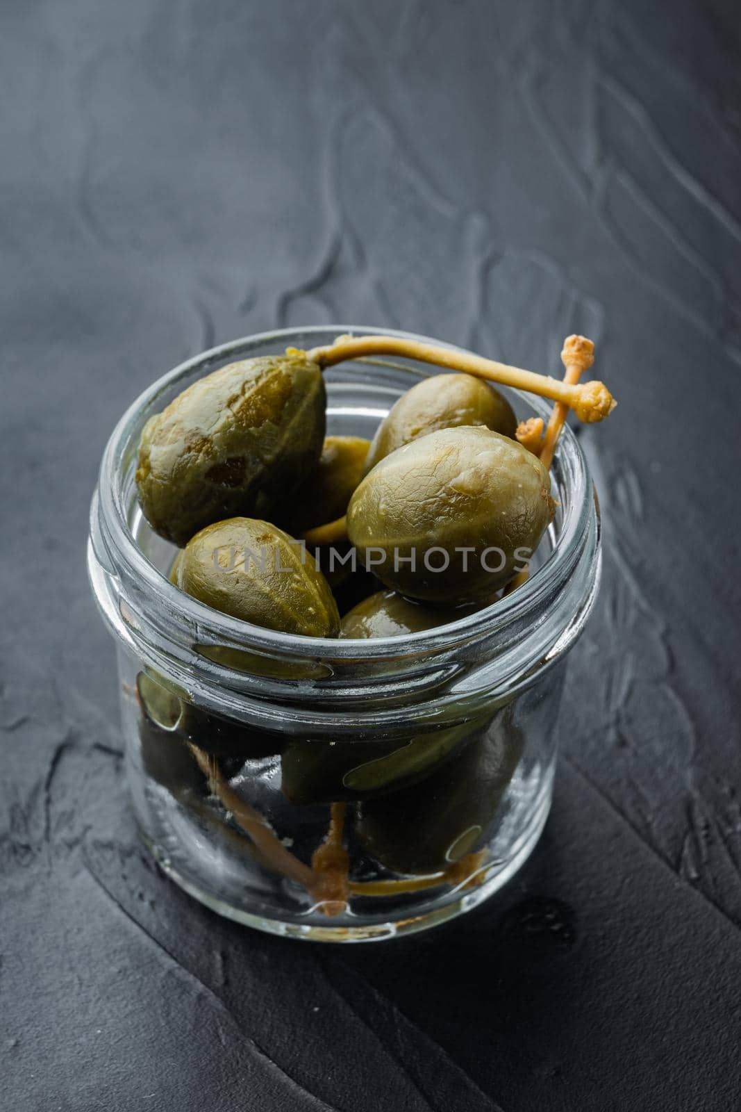 Organic pickled, canned capers, on black background