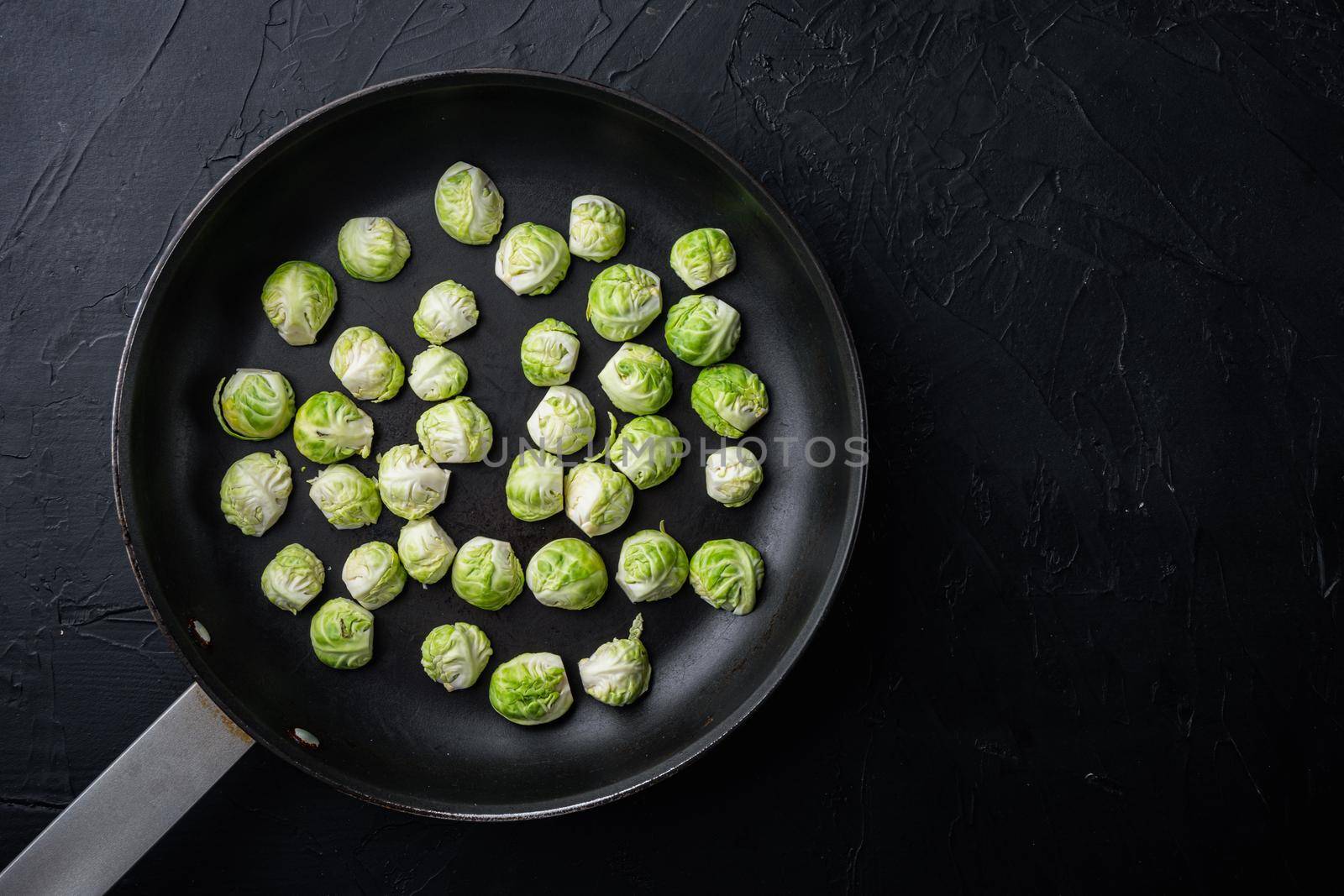 Raw brussels sprouts, on black textured background, top view with space for text