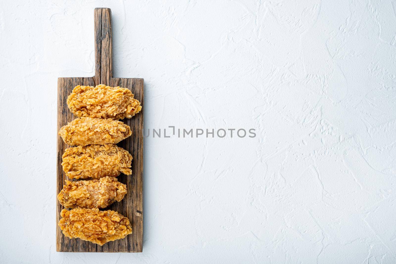 Spicy deep fried breaded chicken wings cuts on white background, top view, with copy space.