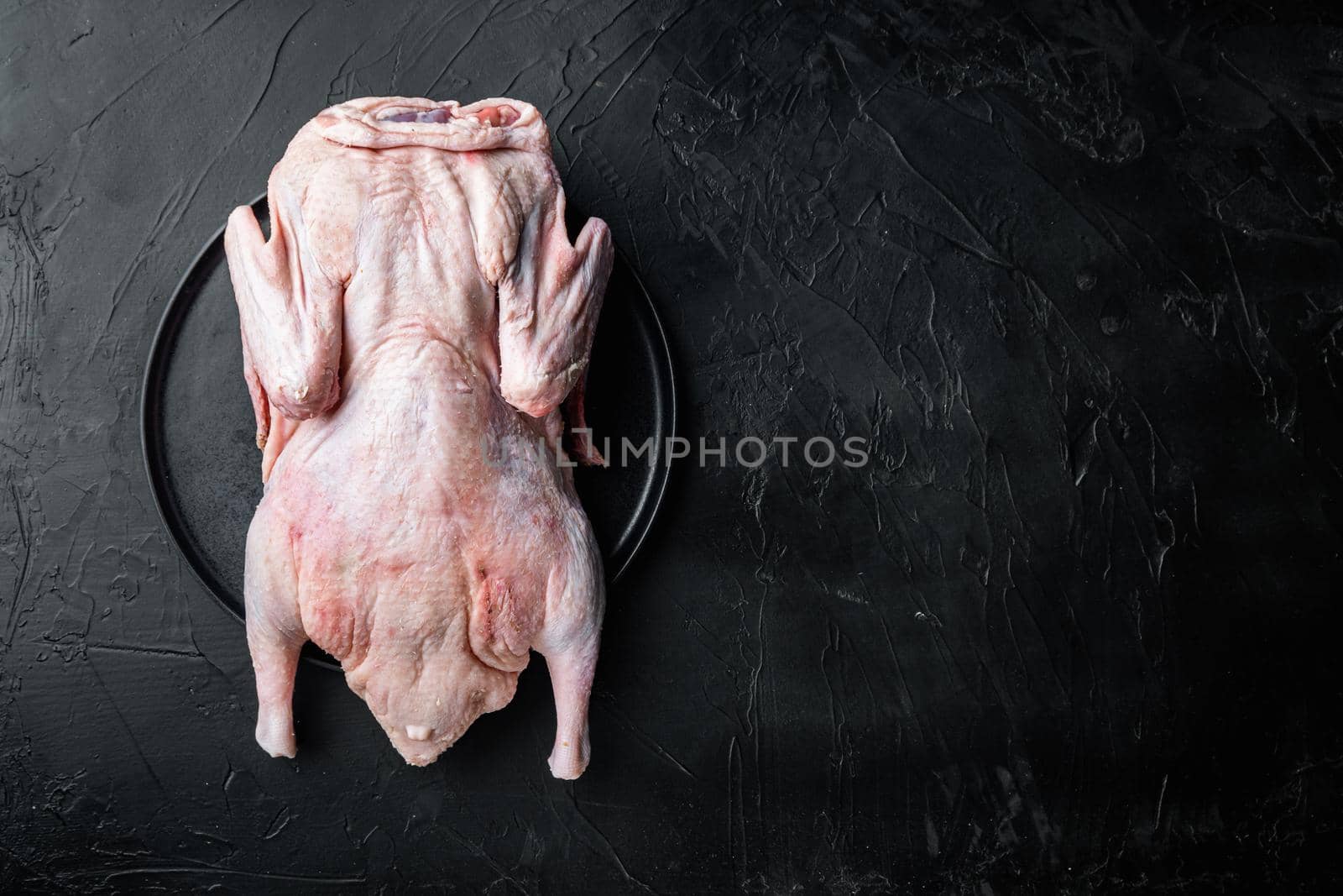 Raw young goose meat on black background, flat lay, with copy space.