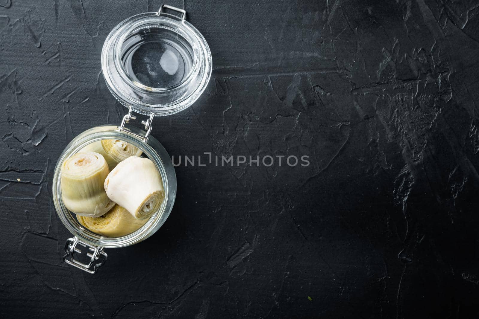 Artichoke hearts set, on black textured background, flat lay with space for text