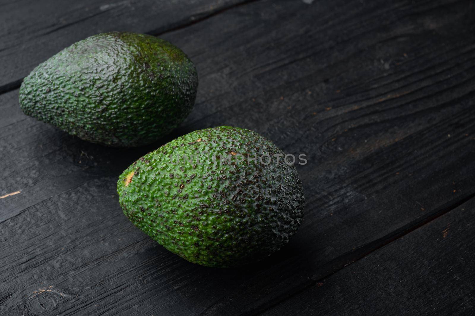 Whole pair of green avocado set, on black wooden background