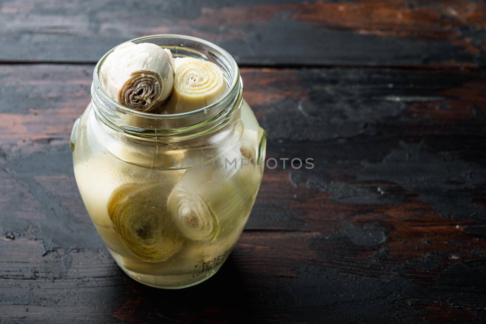 Canned artichokes with olive oil, on old wooden table with space for text