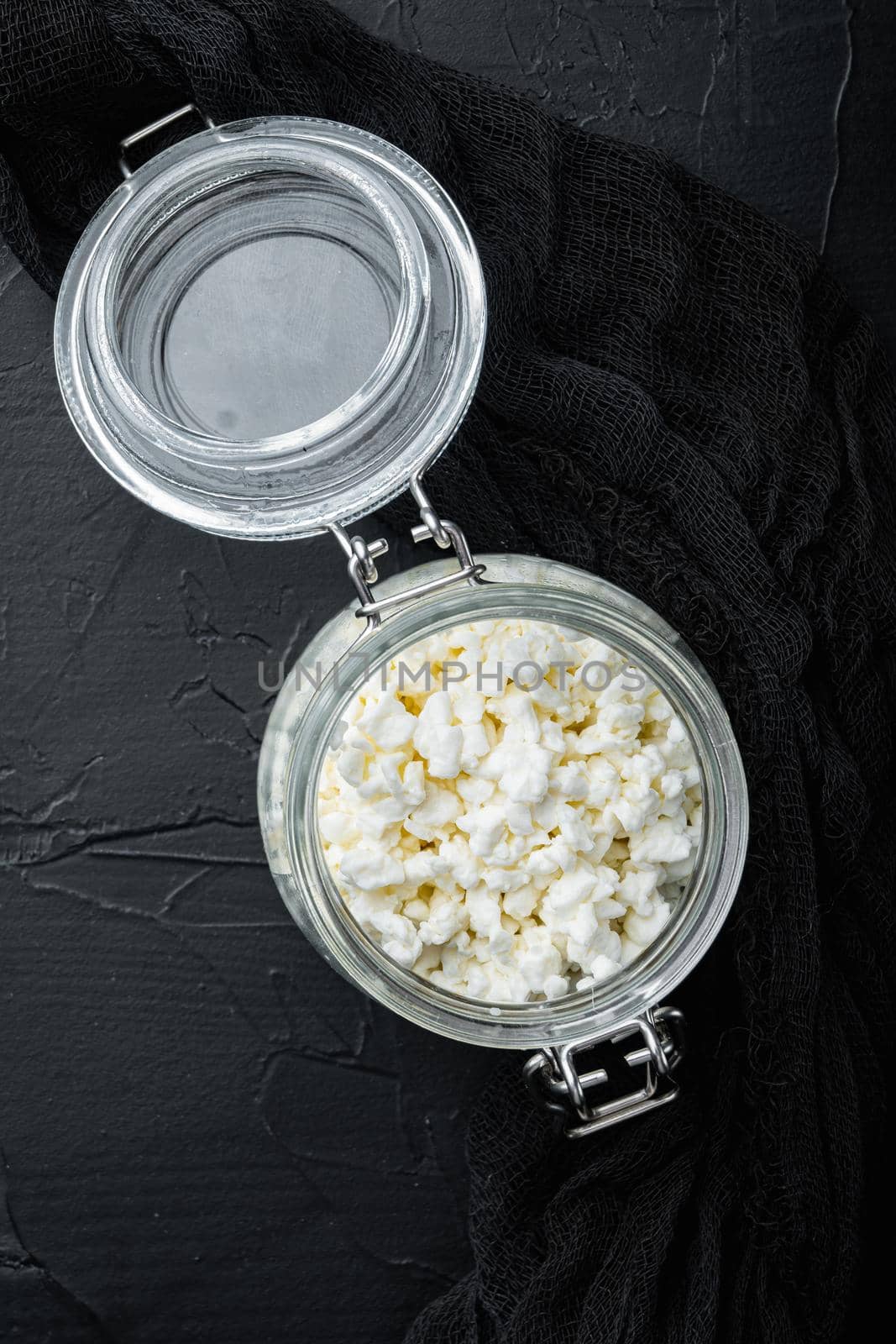 Cottage cheese, curd, on black textured background, top view