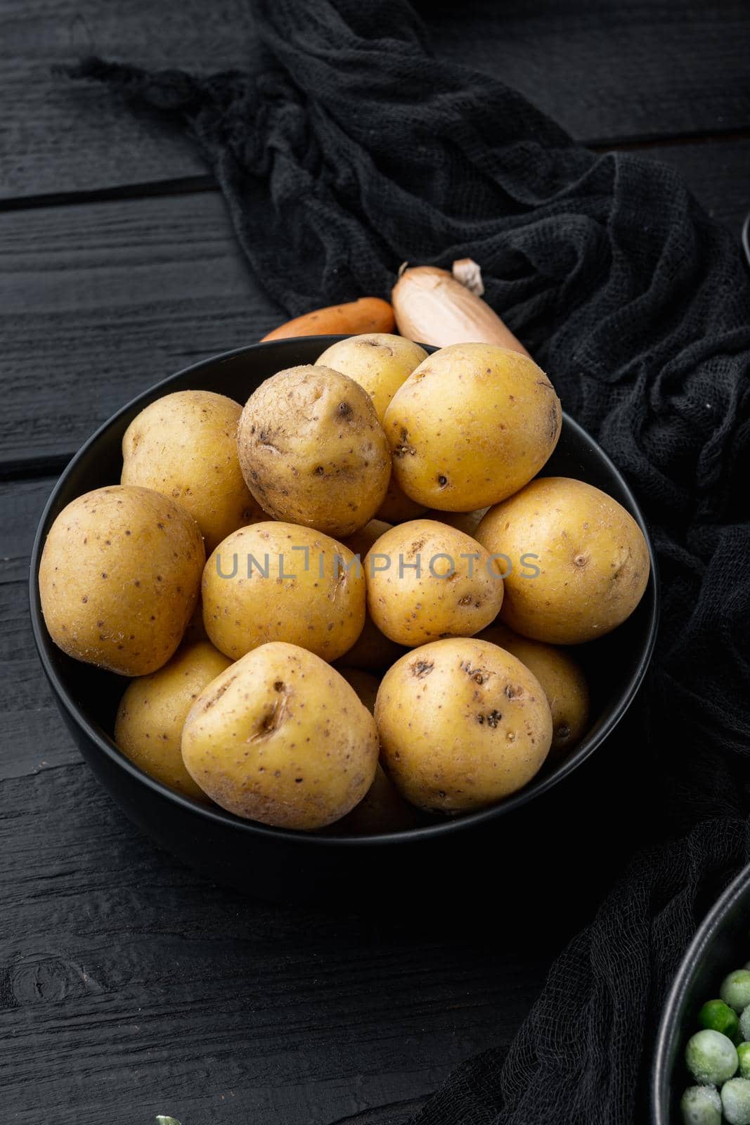 Fresh unpeeled, baby potatoes, on black wooden background