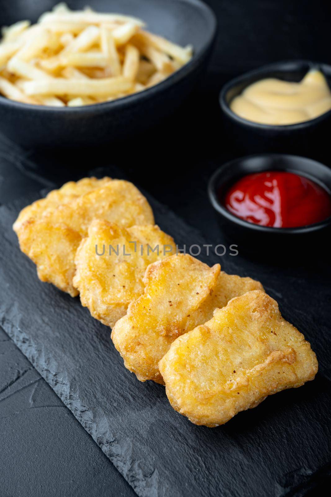 Chicken breast nuggets fried on black background.