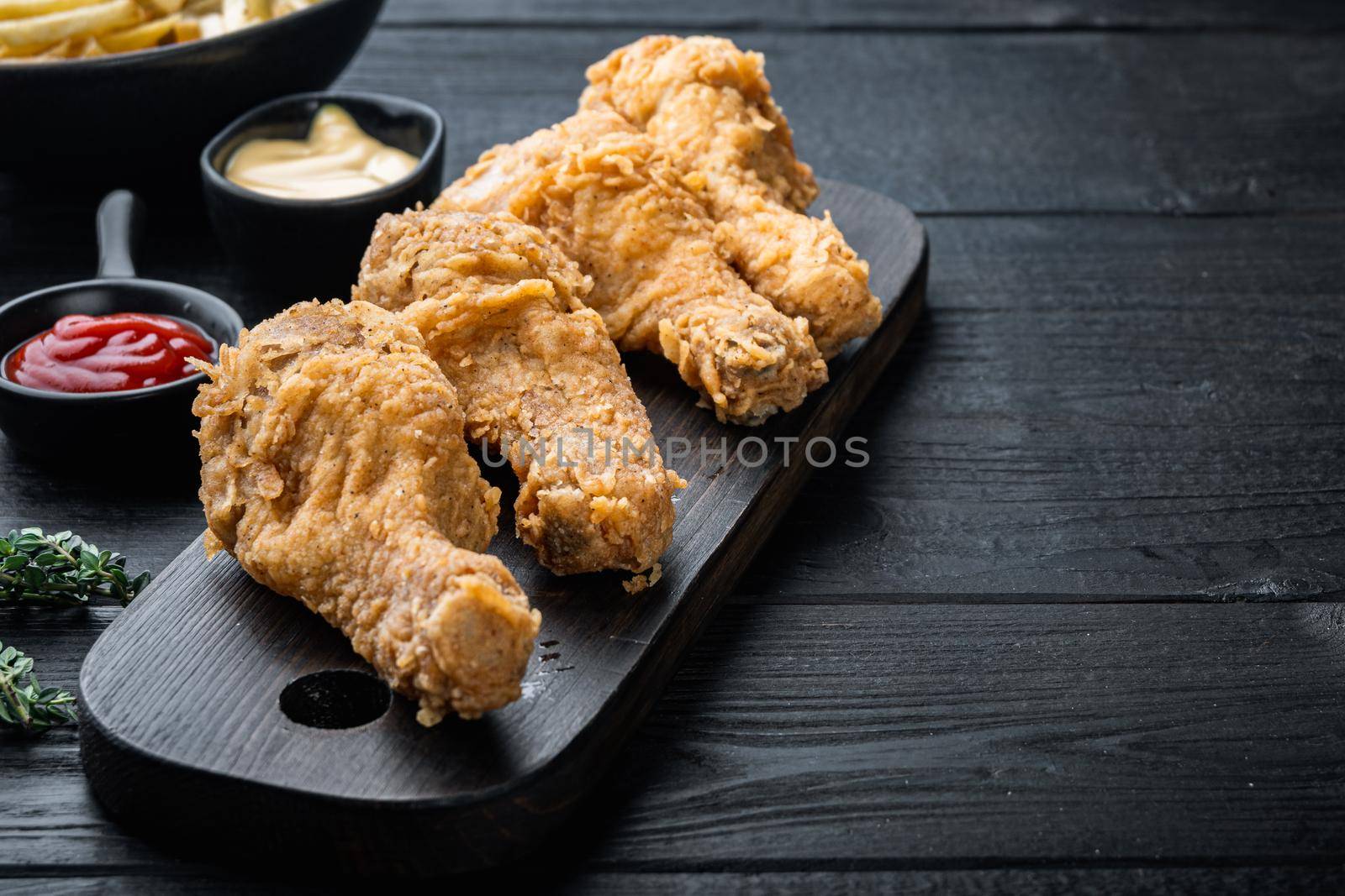 Chicken leg breaded and fried on black wooden table, with copy space.