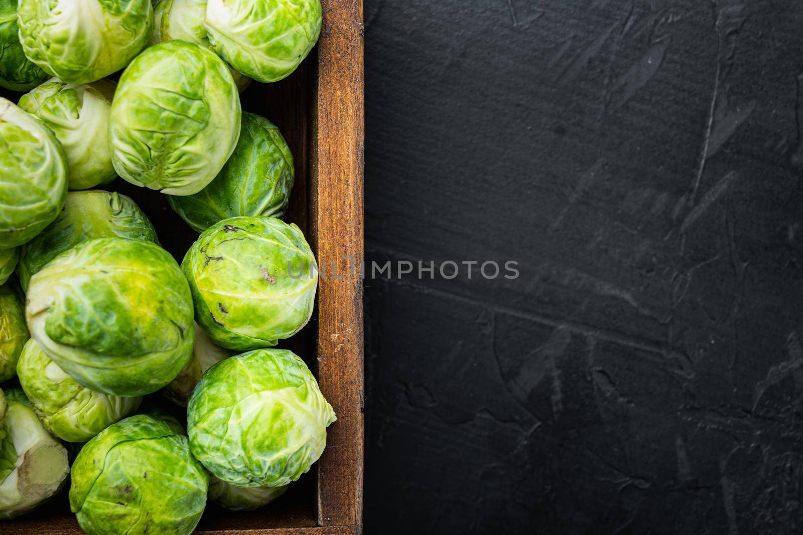 Raw brussels sprouts, on black textured background, top view with space for text