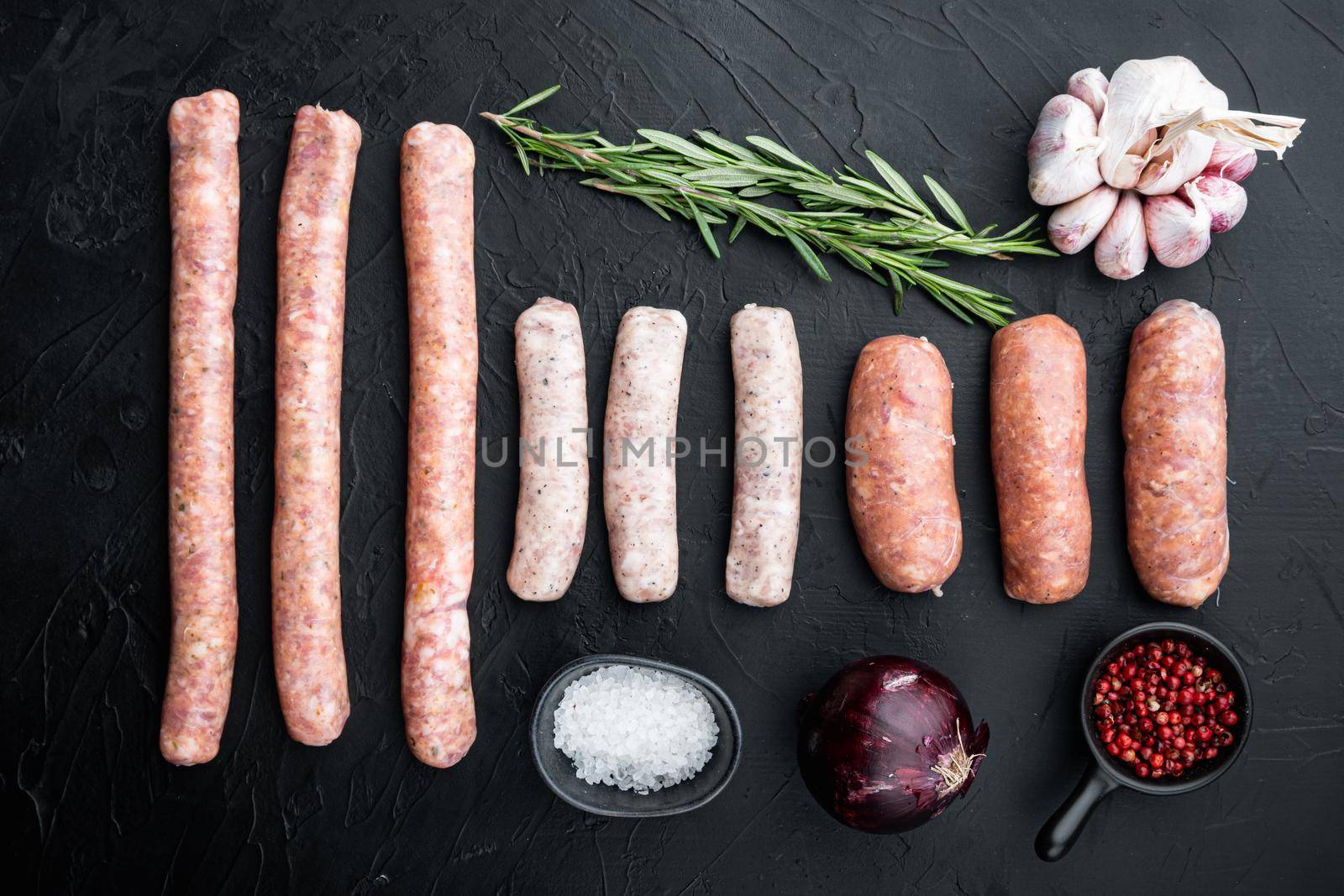 Raw sausages set, top view, on black background.