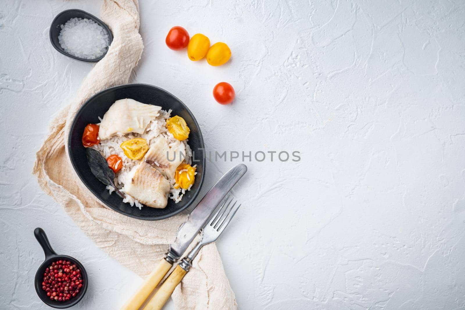 Tilapia fish with basmati rice and cherry tomatoes, in bowl, on white background, top view with copy space for text