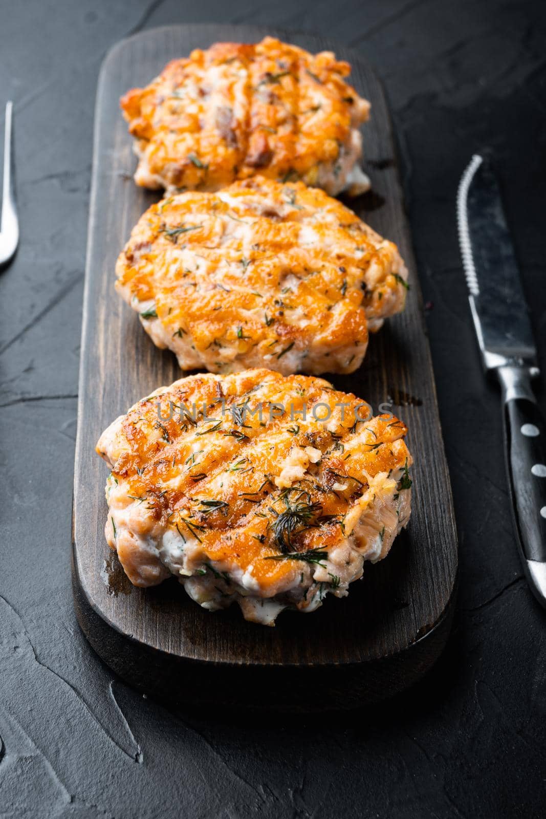 Grilled fishcakes set, on black textured background