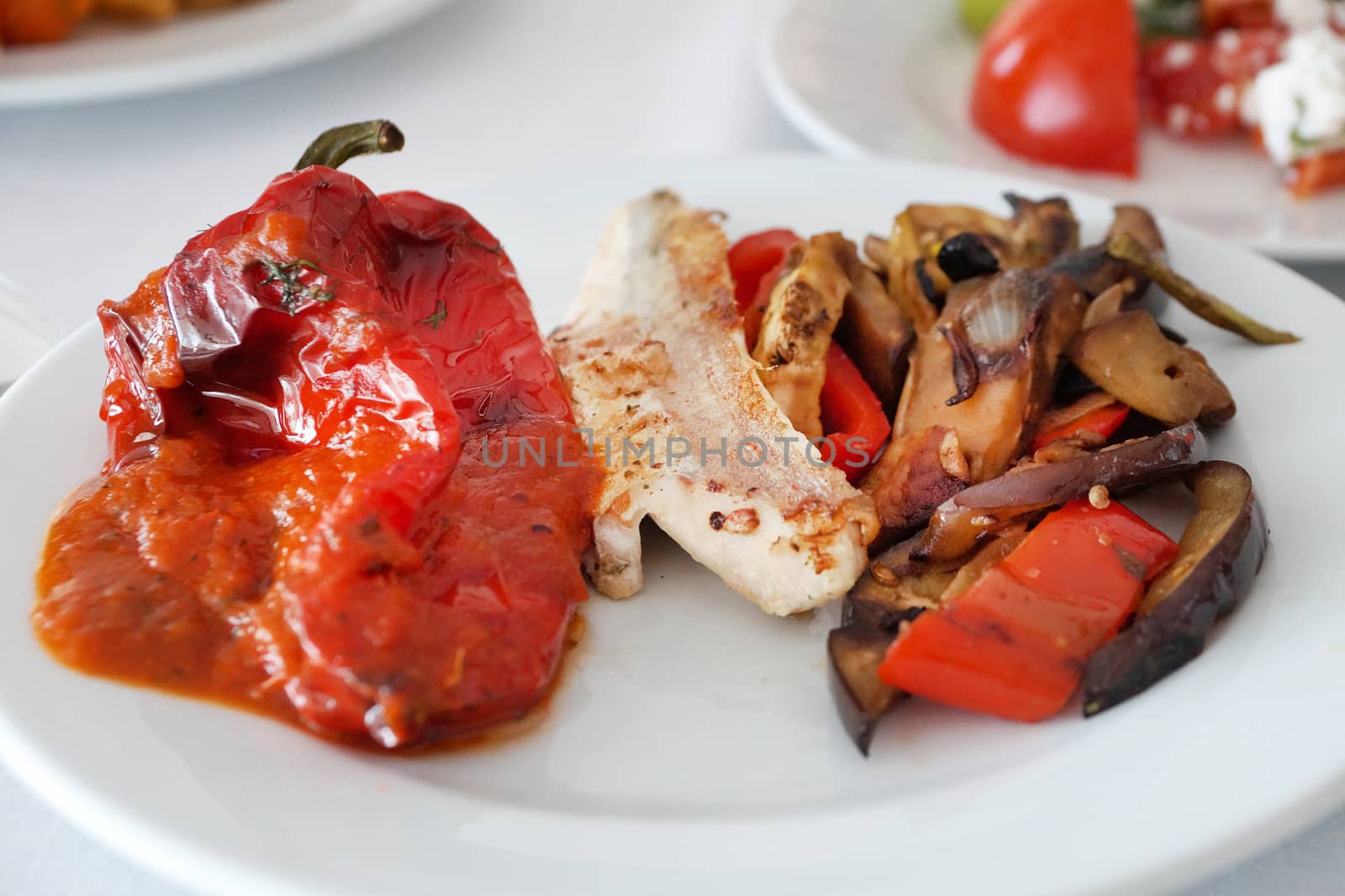 fish fillet with baked peppers and vegetables on a plate close-up