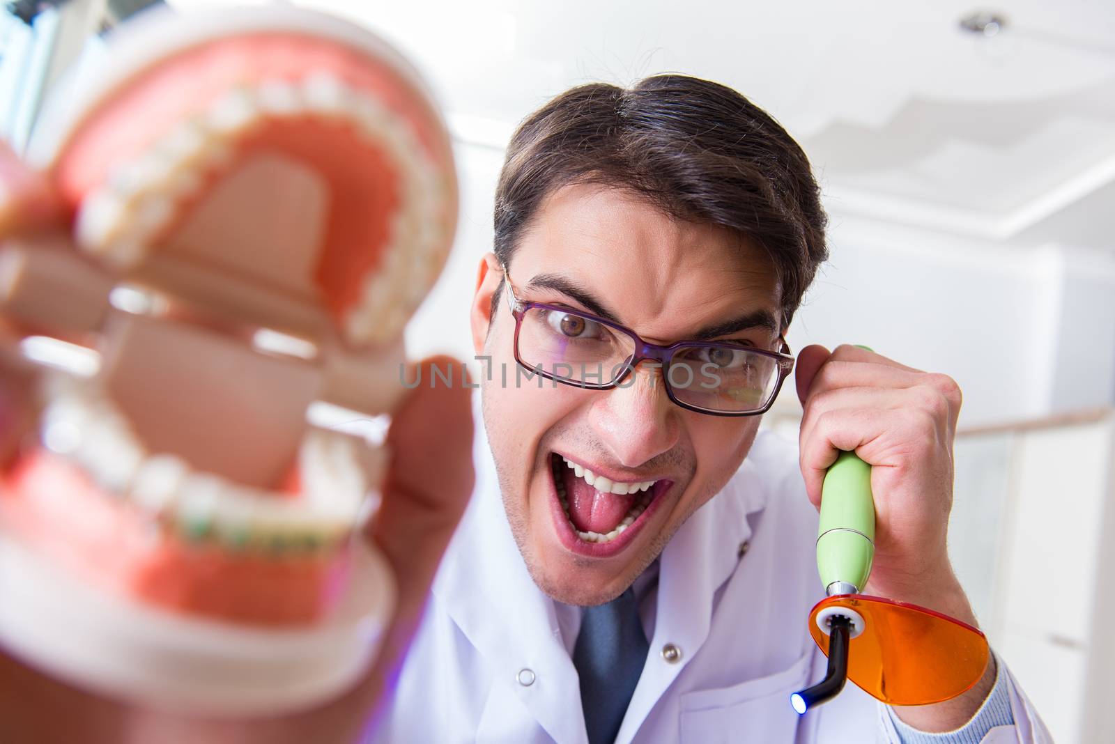 Funny dentist with curing light in medical concept