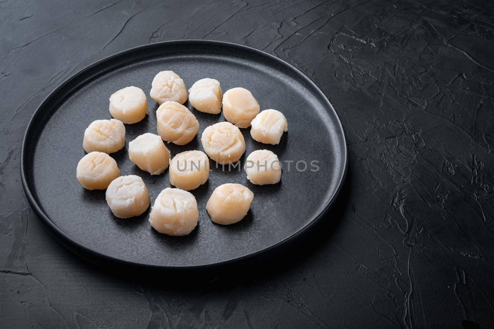 Sea delicacies, raw scallops, on black textured background with copy space