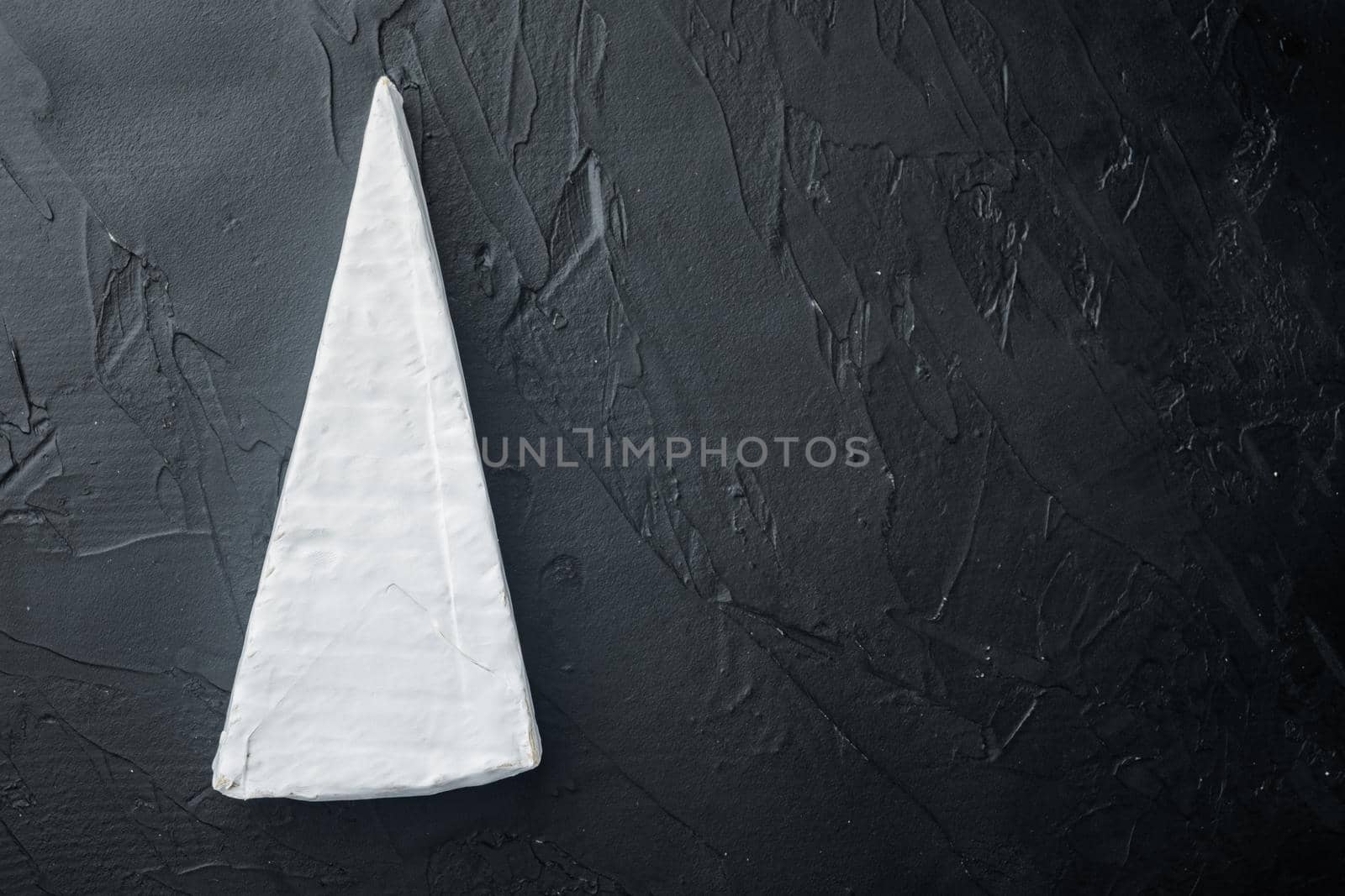 Brie type of cheese set, on black background, flat lay with copy space for text