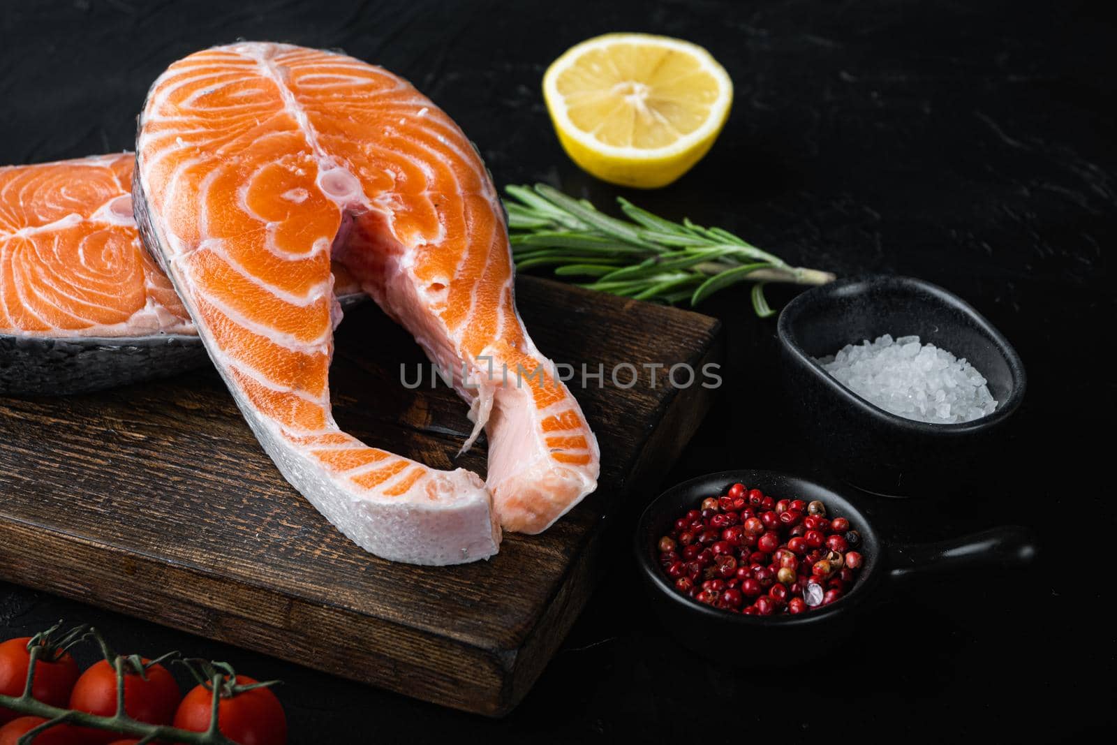 Slice of red fish trout with herbs, over black background.