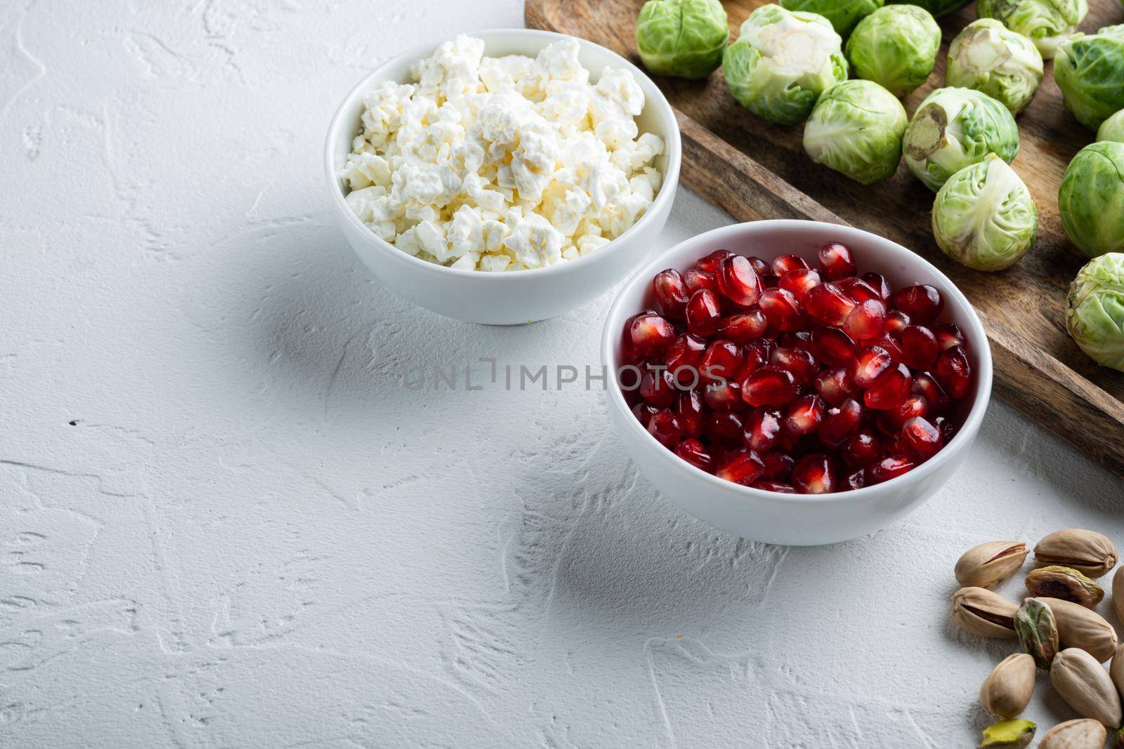 Ripe pomegranate with juicy seeds, on white textured background with space for text