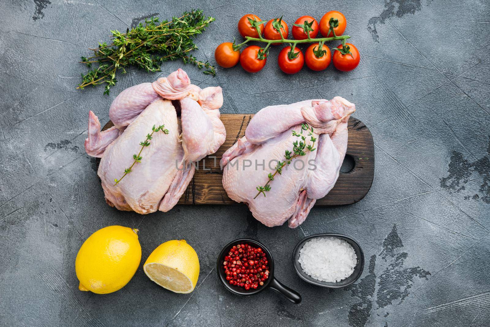 Fresh raw chicken meat with herbs and ingredients, on gray background, top view