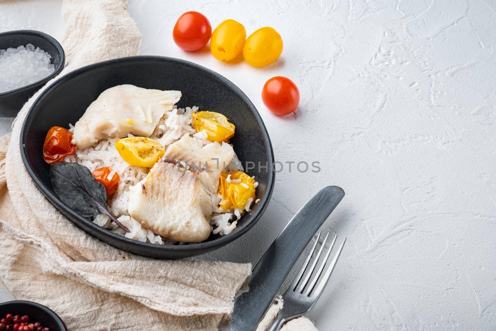 Tilapia fish with basmati rice and cherry tomatoes, in bowl, on white background with copy space for text