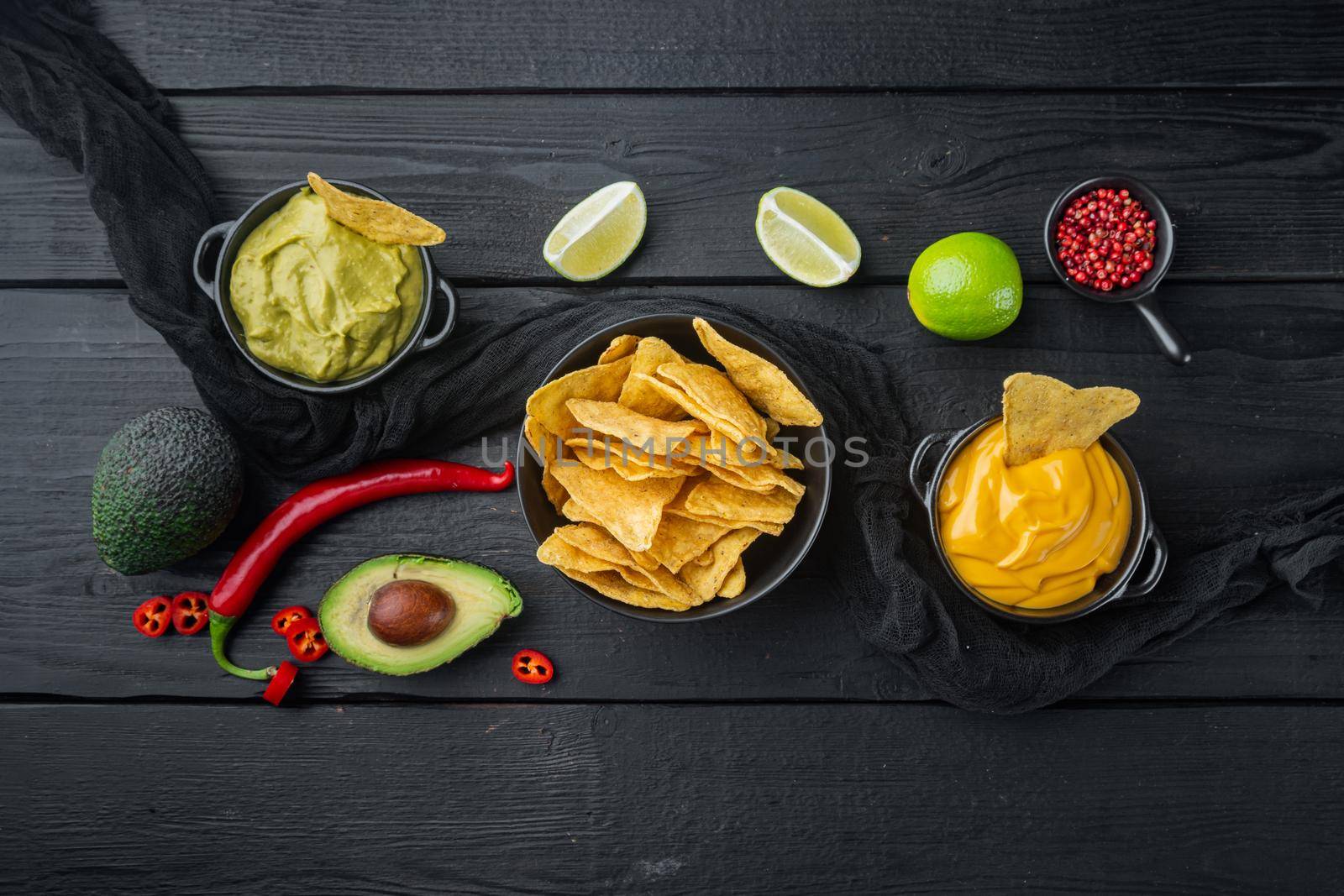 Mexican nachos with sauce set, on black wooden background, top view or flat lay with copy space for text