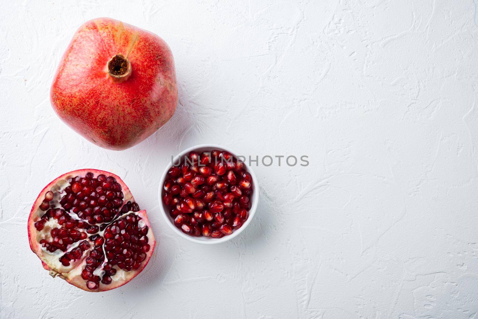 Ripe pomegranate with juicy seeds, on white textured background, top view with space for text