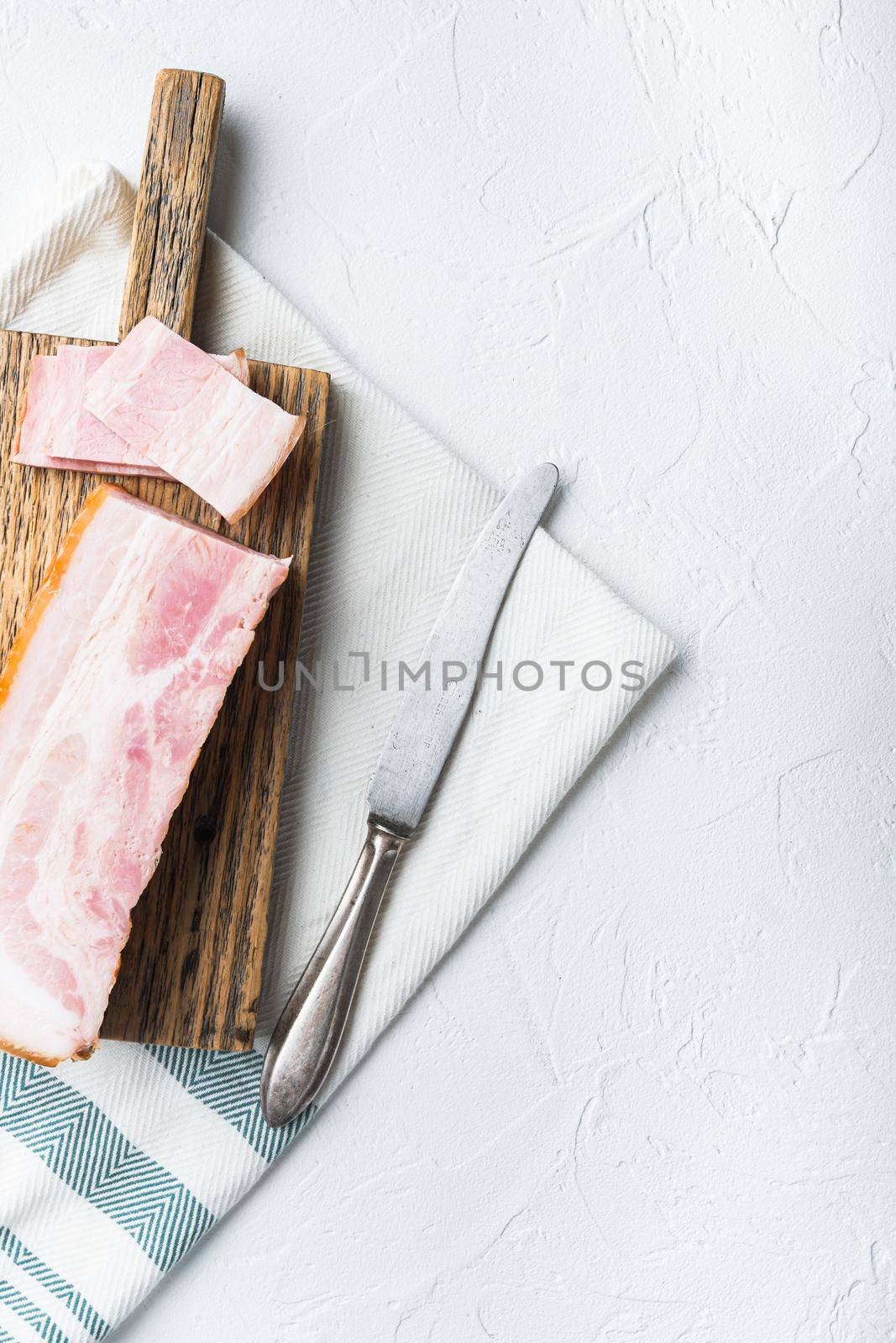 Bacon pancetta cut and sliced on white background, top view with space for text.