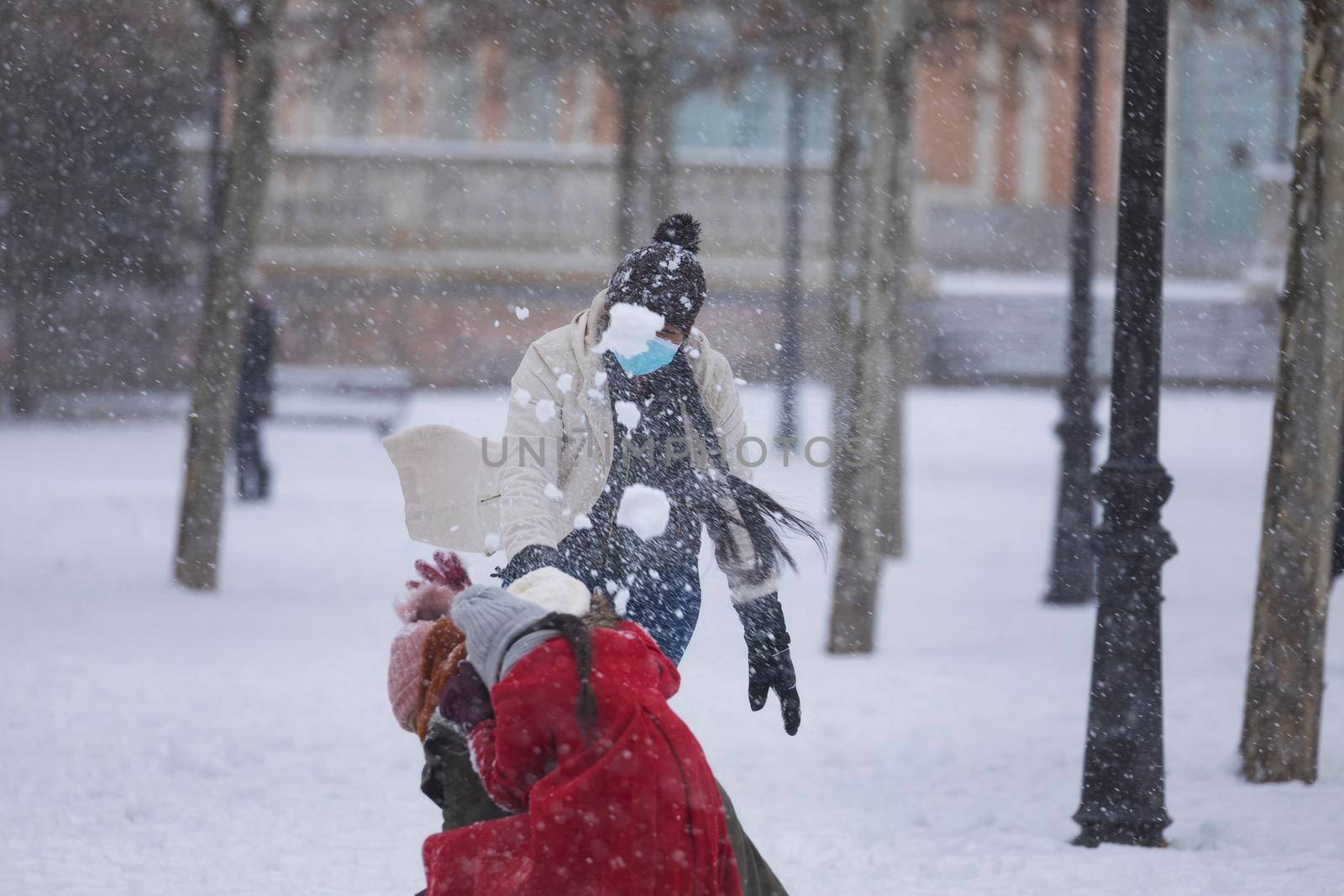 Madrid, Spain - January 08, 2021: Happy people playing to throw snowballs in the Buen Retiro park in Madrid, in the middle of a snowy day, due to a wave of polar cold.