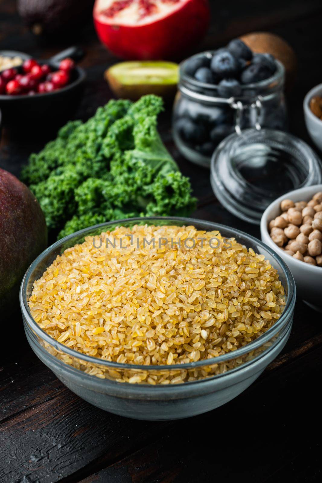 Bulgur grain in bowl on dark wooden background.